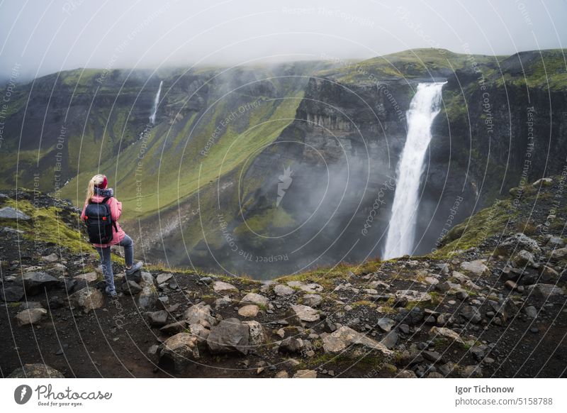 Frau mit Rucksack und fliederfarbener Jacke genießt den Haifoss-Wasserfall im isländischen Hochland im Thjorsardalur-Tal haifoss Tourist reisen Natur