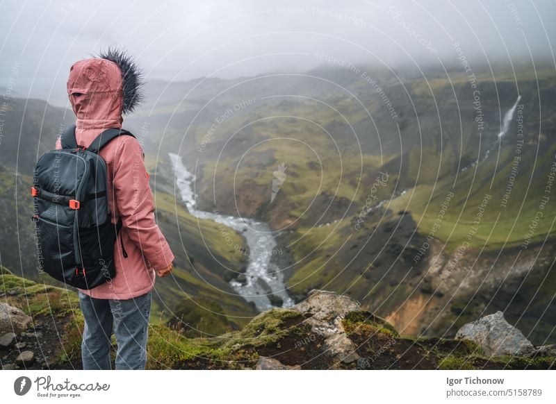 Frau in fliederfarbener Jacke mit Rucksack genießt isländisches Hochland und Flussfossa in der Nähe des Haifoss-Wasserfalls in Island haifoss Tourist reisen