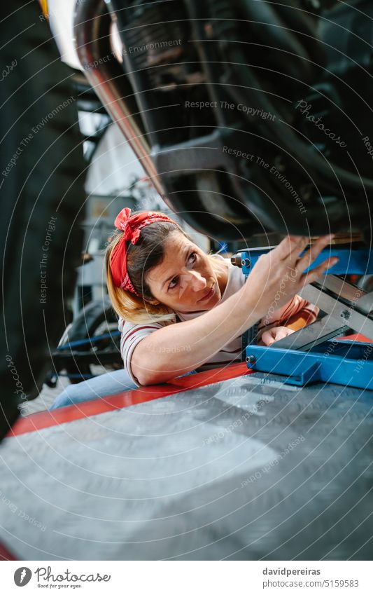 Mechanikerin überprüft Motorrad auf der Plattform Frau Arbeiter Überprüfung arbeiten überblicken Reparatur Fabrik Garage Werkstatt Podest Besichtigung