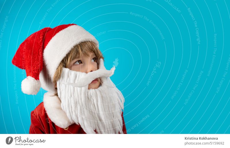 Porträt eines niedlichen Jungen mit Weihnachtsmannmütze und Bart auf Blau. Weihnachtsbanner 4 Jahre alt bezaubernd künstlicher Bart Baby Baby-Weihnachtsmann