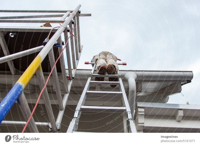 Dachdecker, Arbeiter auf dem Dach, auf einer Leiter stehend. Dacharbeiten. Gerüst auf der Baustelle Architektur Gebäude Bautätigkeit Geschäft Bauindustrie