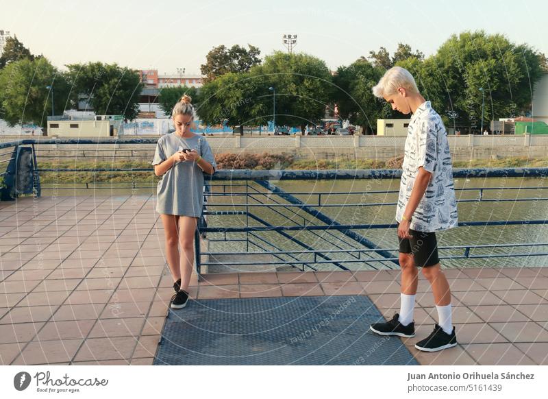 Mädchen tippt auf ihrem Mobiltelefon in der Nähe eines Jungen Jugendzeit Menschen jung Jugendlicher gutaussehend niedlich Nizza glückselig Freundschaft Freunde