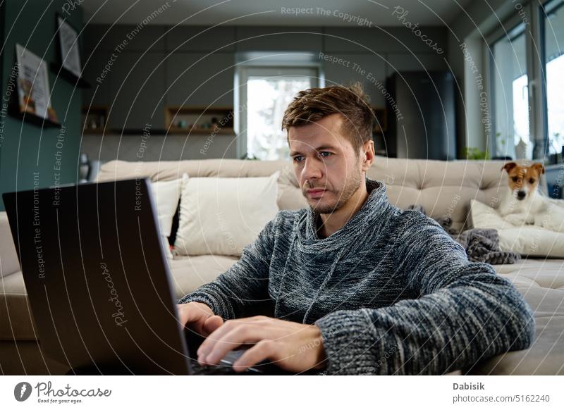 Mann benutzt Laptop im Wohnzimmer Arbeit heimwärts abgelegen Lifestyle online Freiberufler Arbeit von zu Hause aus Hund Haustier beschäftigt Business
