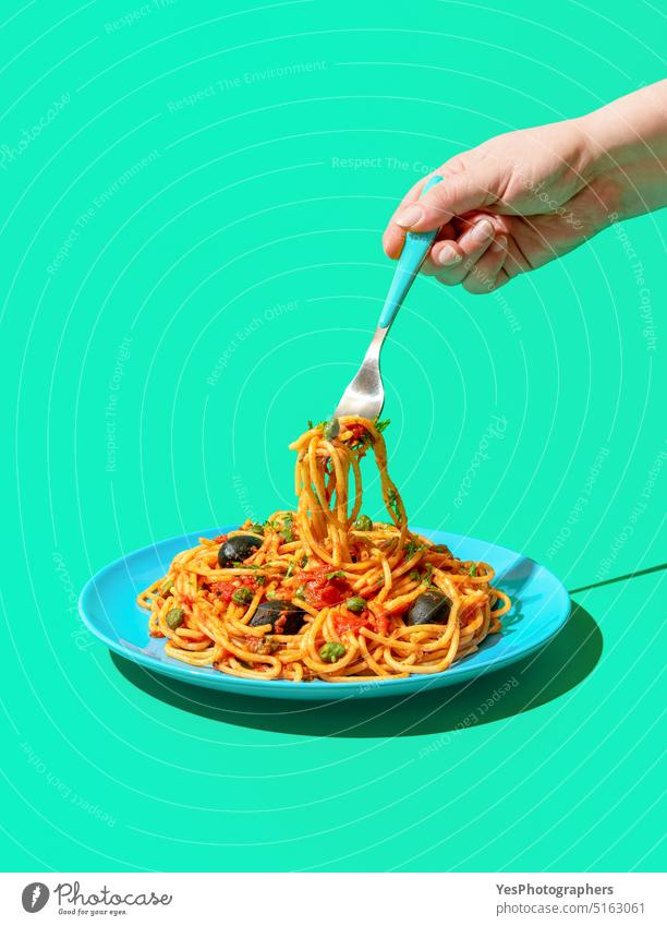 Spaghetti Puttanesca, ein veganes Nudelgericht, minimalistisch auf grünem Hintergrund essen blau hell Kapriolen Kohlenhydrate Nahaufnahme Farbe gekocht
