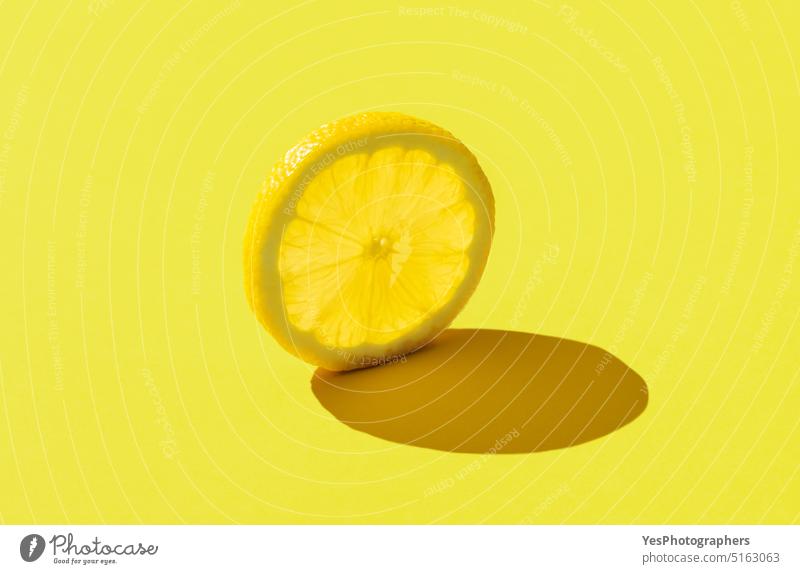 Zitronenscheibe minimalistisch auf einem gelben Hintergrund abstrakt hell Zitrusfrüchte Nahaufnahme Farbe farbenfroh Konzept Textfreiraum kreativ Küche