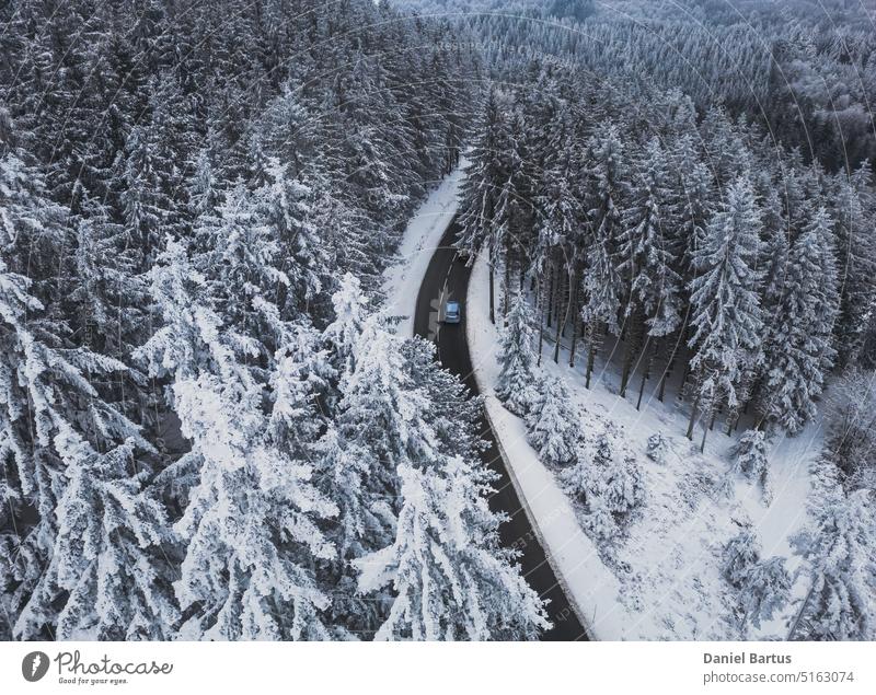 Schneebedeckte Bäume im Wald und asphaltierte Straße in den Bergen. Winterlandschaft in den Bergen. Aerial Drohne Panoramafoto. oben Antenne Luftbildfotografie