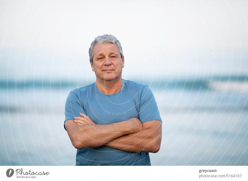 Porträt eines älteren Mannes auf unscharfem Meereshintergrund Senior Strand in den Ruhestand getreten Menschen MEER männlich verschränkte Arme gekreuzt reif
