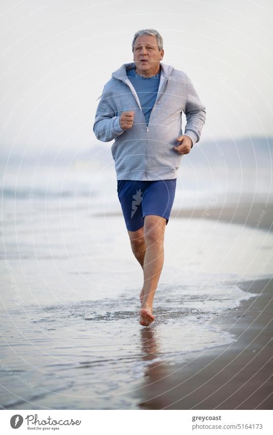 Aktiver älterer Mann joggt am Strand entlang Joggen Training in den Ruhestand getreten Menschen Senior Sport laufen joggen männlich aktiv Übung Läufer