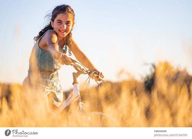Nettes Mädchen mit ihrem Fahrrad im Sommer. aktiv Schönheit Radfahren Blauer Himmel Kaukasier Kind Landschaft Zyklus Fahrradfahren Radfahrer trocknen Frau Feld