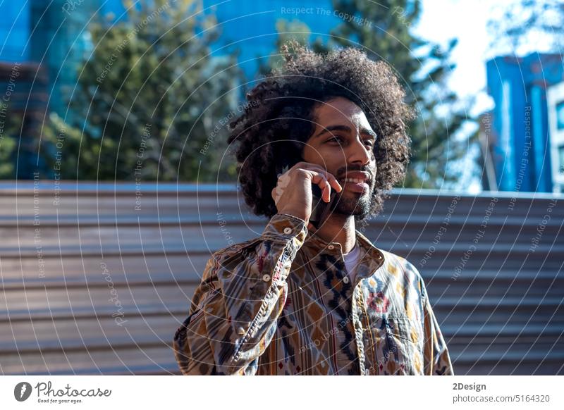 Junger Afro-Mann benutzt Handy im Freien Baustein Afro-Look Telefon Mobile Beteiligung Porträt männlich Typ Stehen Funktelefon Wand Lehnen Afrikanisch