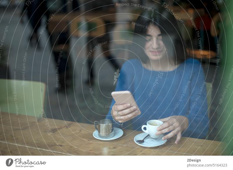 Lächelnde Frau in einem Café, die ein Mobiltelefon benutzt und in sozialen Netzwerken SMS schreibt, allein sitzend Telefon benutzend Bar Technik & Technologie