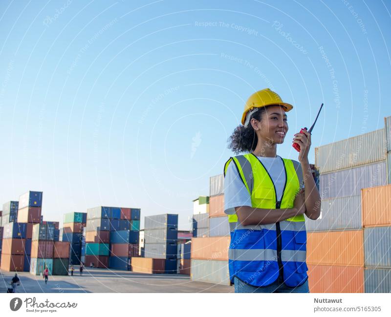 Female safety hardhat yellow helmet african america black skin person talkie walkie radio labor engineer woman people control warehouse terminal shipping import export container business technology
