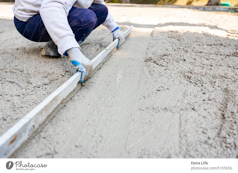 Arbeiter nivelliert frischen Beton nach dem Gießen Ausrichten Basis Bauherr Baustelle Zement Tiefbau betonieren Konstruktion Entzerrung Gleicht  aus. Entspricht