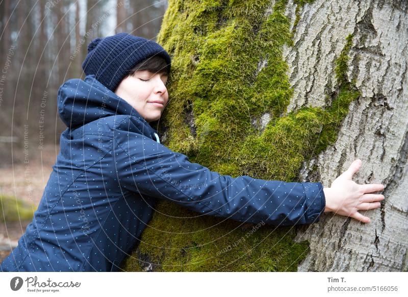Frau mit Pudelmütze umarmt einen Moosbewachsenen Baum Wald Brandenburg Natur Außenaufnahme Farbfoto Umwelt Landschaft Tag Pflanze grün Herbst Schönes Wetter