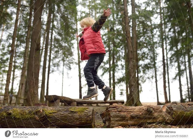 Kleiner Junge in roter Weste spielt Zweig und hat Spaß im Wald am frühen Frühlingstag. Aktivität für Kinder. Outdoor-Erholung für die Familie Natur Totholz
