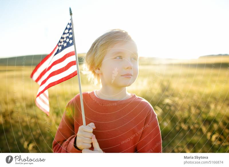 Stolzer kleiner amerikanischer Junge hält seine Landesflagge USA Fahne stolz Kind uns Kaukasier weiß Juli 4 Amerikaner niedlich Sonnenuntergang winkend Sommer