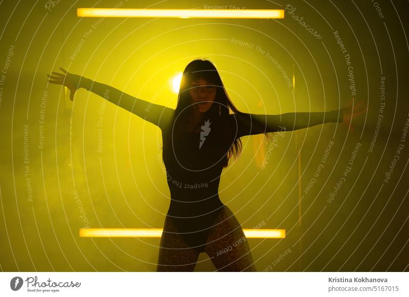 Sexy Frau tanzt auf gelben led Lampen dunstigen Hintergrund. Sie sieht verführerisch aus. Erwachsener attraktiv hintergrundbeleuchtet schön Schönheit Körper