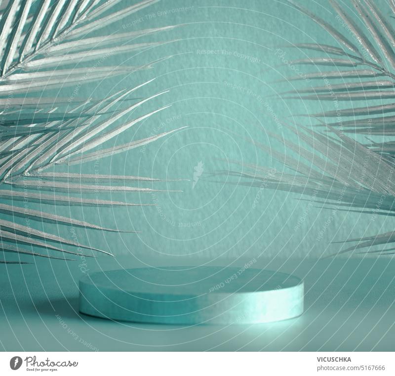 Metallisch türkisfarbenes Produktdisplay mit Podest und silbernen Palmenblättern, Vorderansicht metallisch Produktpräsentation Podium Silber Objekt Werbung