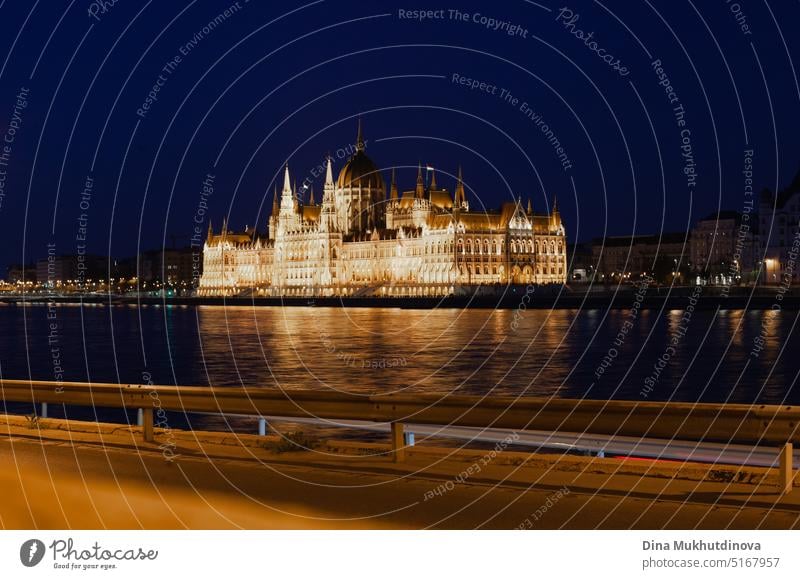 Ungarisches Parlamentsgebäude in Budapest, das sich nachts im Wasser der Donau spiegelt, fotografiert an einem sonnigen Tag mit blauem Himmel. Domed neugotischen Stil Architektur. Berühmte Wahrzeichen für Sightseeing in Ungarn Postkartenansicht.