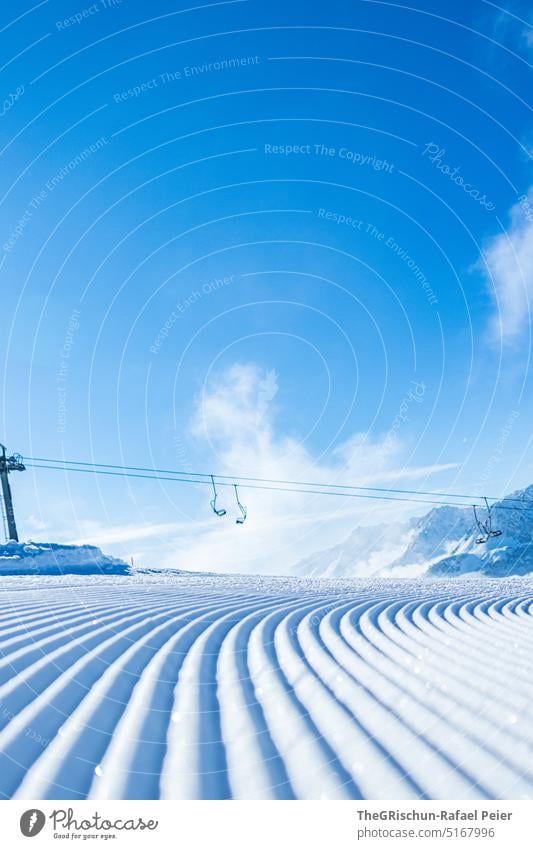 Frische Piste mit Sessellift im Hintergrund vor blauem Himmel Schnee Loipe sessellift Skigebiet Blauer Himmel kalt Muster Winter Wintersport Skifahren