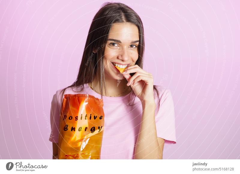 Frau isst leckere Chips rosa Hintergrund Lächeln positiv Energie nacho essen knusprig genießen Snack Leckerbissen farbenfroh geschmackvoll Schwingung Optimist
