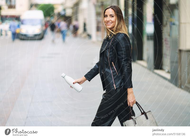 Smart casual Dame mit Tasche und Flasche zu Fuß auf der Straße Frau Arbeitsweg Stil Spaziergang urban Stadt selbstbewusst trendy Zeitgenosse modern