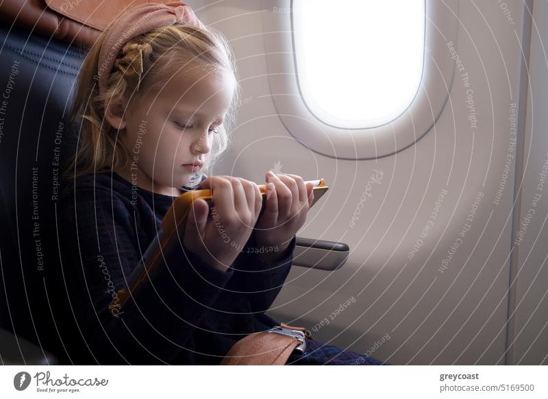 Konzentriertes Mädchen schaut im Flugzeug ein Video auf dem Tablet Kind Konzentration Tablette benutzend zuschauen Passagier Apparatur Karikatur Ebene Browsen