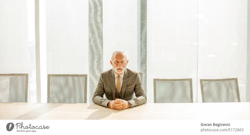 Ein älterer Geschäftsmann sitzt im Sitzungssaal seines Büros Erwachsener gealtert Vollbart Chef Business Kaukasier Kollegen Unternehmen selbstbewusst korporativ
