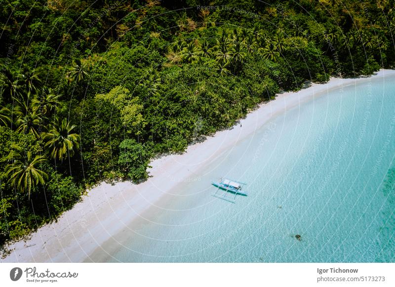 Aerial Drohne Blick auf eine schöne einsame verlassenen tropischen Strand. Einsames Boot in türkisfarbener Lagune vor Regenwald-Dschungel. Cadlao Insel, El Nido, Palawan