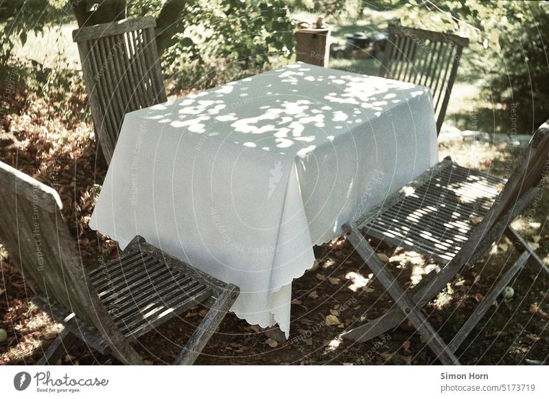 Tisch im Garten Sommer Tischdecke Schatten idyllisch friedlich puristisch Wärme ausruhen essen Treffpunkt Erholung Pause sitzen ruhig Bank Außenaufnahme grün