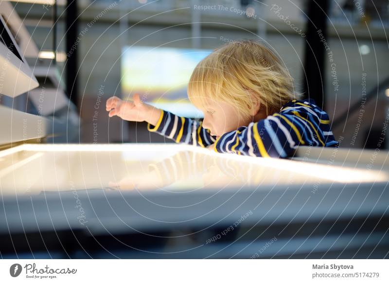 Kleiner kaukasischer Junge sieht sich eine Ausstellung in einem wissenschaftlichen Museum an. Keen Kind ist die Erforschung der Exponate. Bildung und Unterhaltung für Kinder. Aktivitäten für die Familie mit Kindern.