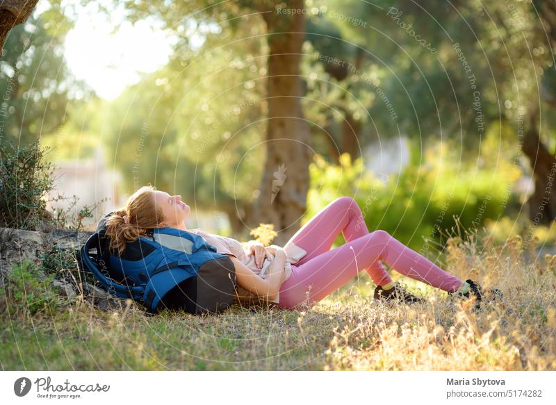 Junge Frau beim Wandern auf dem Lande. Das Mädchen liegt unter einem Baum und entspannt sich. Konzepte von Abenteuer, extremes Überleben, Orientierungslauf. Einzelne Reise. Backpacking