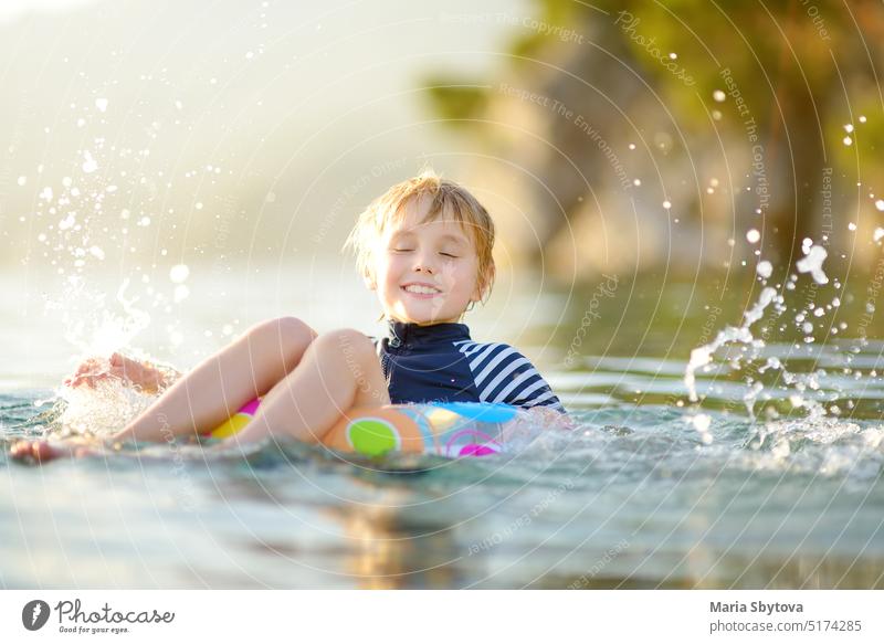 Kleiner Junge schwimmen mit bunten schwimmenden Ring im Meer auf sonnigen Sommertag. Nettes Kind spielt in sauberem Wasser. Familie und Kinder Resort Urlaub während der Sommerferien.