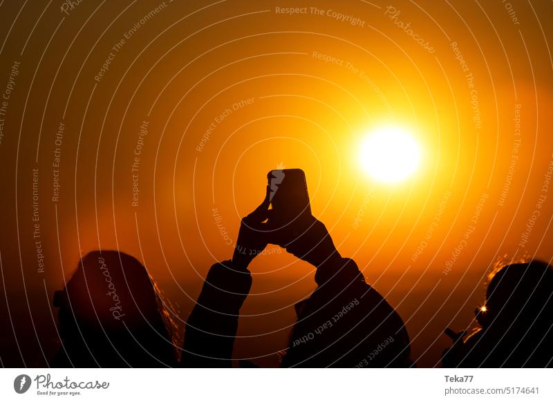 eine Person macht ein Foto mit einem Smartphone in der Abendsonne Person mit einem Smartphone Schatten Personenschatten Sonnenuntergang Menschen