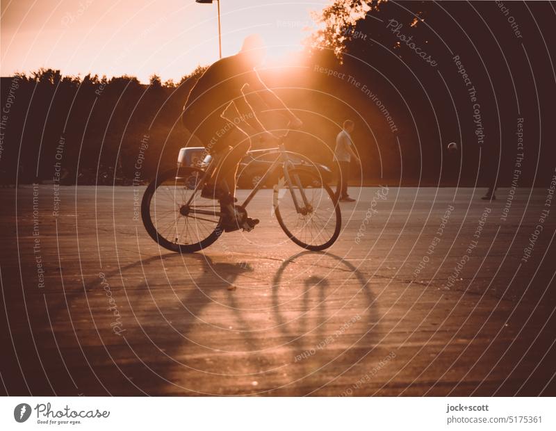Kunstradfahren in der Abendsonne, rückwärtsfahren die ganze Zeit Fahrrad Fahrradfahren Sport Radfahren Lifestyle im Freien Gegenlicht Mann junger Erwachsener