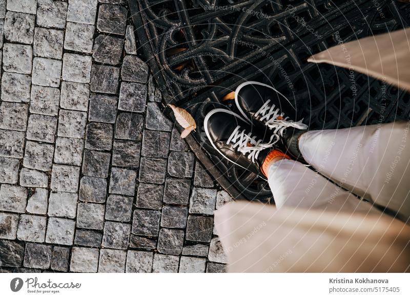 Weibliche Beine in Turnschuhen auf Pflastersteinen. Teenager-Füße von oben gesehen. Prager Straße abstrakt Erwachsener Hintergrund schwarz Klotz Baustein