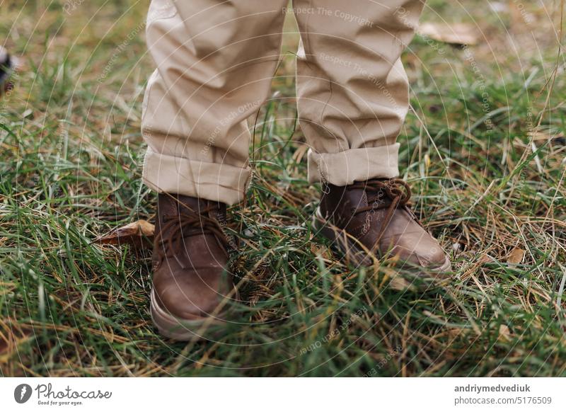 Cropped Foto von Kindern Beine in Leder braune Schuhe und beige Hosen im Freien im Herbst Park mit Ahornblättern Kinder Abenteuer an der frischen Luft. Internationaler Tag der Kinder
