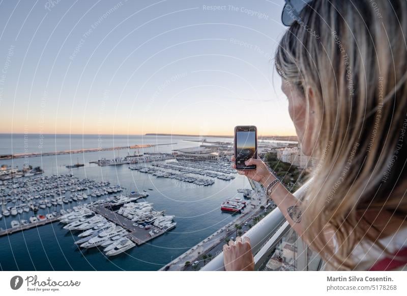 Frau fotografiert den Hafen von Alicante von einer Hotelterrasse in Spanien aus. Erwachsener Alacant alicante Architektur Strand schön blau Fotokamera lässig