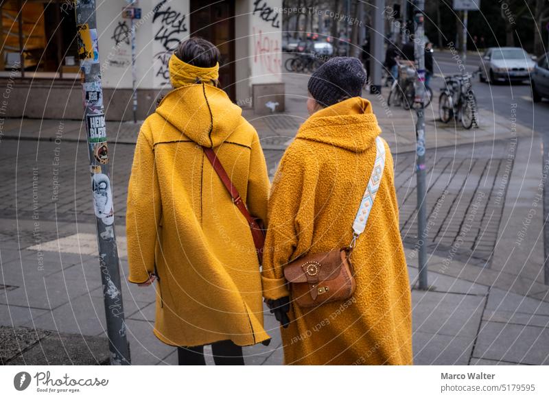 Zwei Frauen in gelben Jacken und Tasche. Zwei Personen Menschen im Freien Straße Mütze Stirnband Fußweg