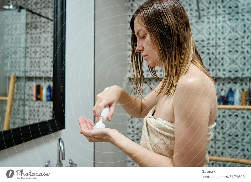 Frau, die ein Schönheitsprodukt zur Haarpflege auf die nassen Haare aufträgt Behaarung Hygiene Bad anwendend Mousse Kosmetik Selbstversorgung Frisur Pflege Kopf
