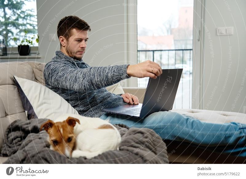 Mann benutzt Laptop im Wohnzimmer Arbeit heimwärts abgelegen Lifestyle online Freiberufler Arbeit von zu Hause aus Hund Haustier beschäftigt Business