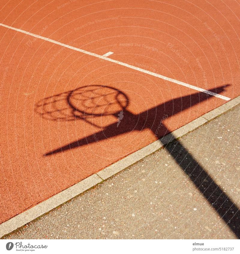 Schatten eines Basketballkorbes mit Netz auf einem roten Sportbodenbelag / Basketball spielen Basketballkorb mit Netz Spielfeld Basketball-Court Korb Ballsport
