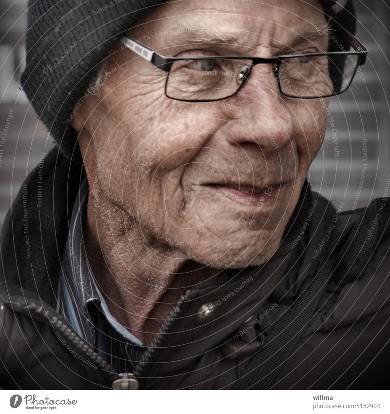 Senior, übertrieben unscharf Porträt Mann Brille Blick zur Seite schmunzeln beobachten kritisch Mütze Anorak gute Laune Alter Runzeln