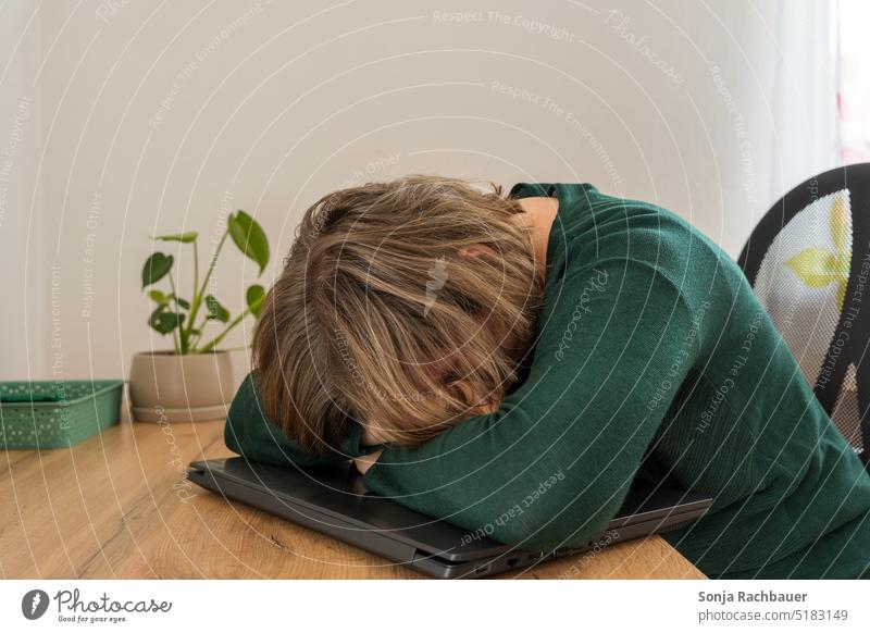 Eine Frau schläft auf einem Laptop an einem Schreibtisch. schlafen Stress Erschöpfung Homeoffice Arbeitsplatz online arbeiten Technik & Technologie Job modern