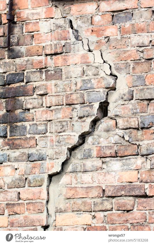 Großer Riss in einer Ziegelsteinmauer Ziegelmauer alt Versatz Standhaftigkeit einsturzgefährdet Einsturzgefahr Backsteinwand kaputt Wand Mauer Menschenleer