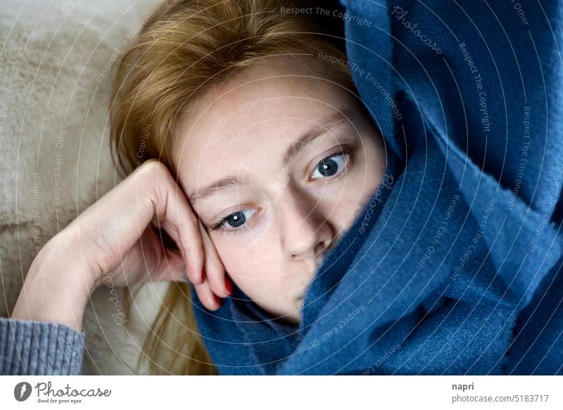 Winterblues | Junge Frau liegt eingekuschelt mit einer flauschigen Decke und starrt deprimiert vor sich hin nachdenklich traurig unglücklich müde allein