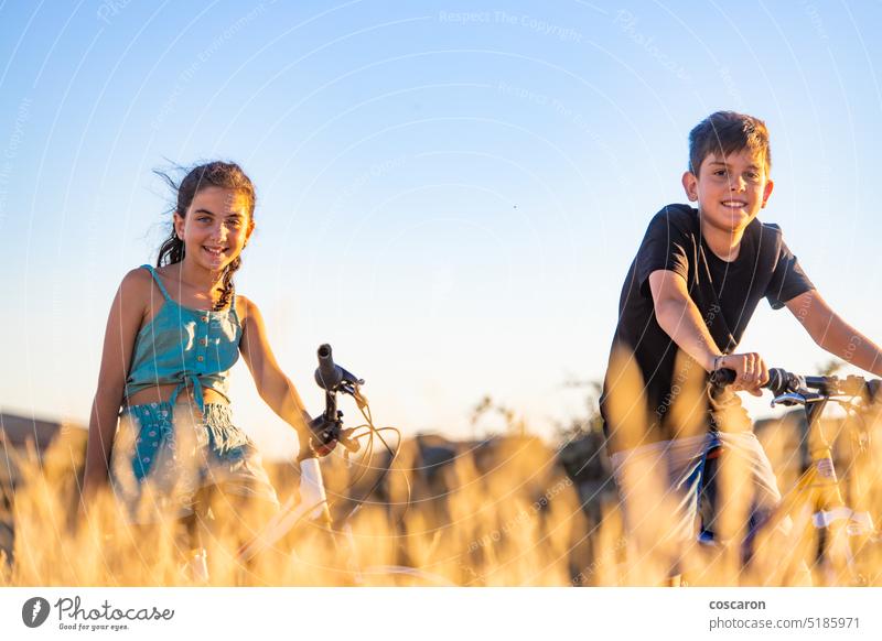 Zwei Kinder auf einem Fahrrad vor einem Weizenfeld Aktionen aktiv Jugendzeit Abenteuer Radfahren Radfahrer Junge Kindheit Land Landschaft Zyklus genießen Übung