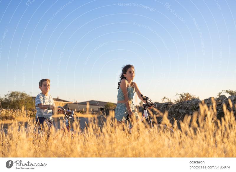 Zwei Kinder auf einem Fahrrad vor einem Weizenfeld Aktionen aktiv Jugendzeit Abenteuer Radfahren Radfahrer Junge Kindheit Land Landschaft Zyklus genießen Übung