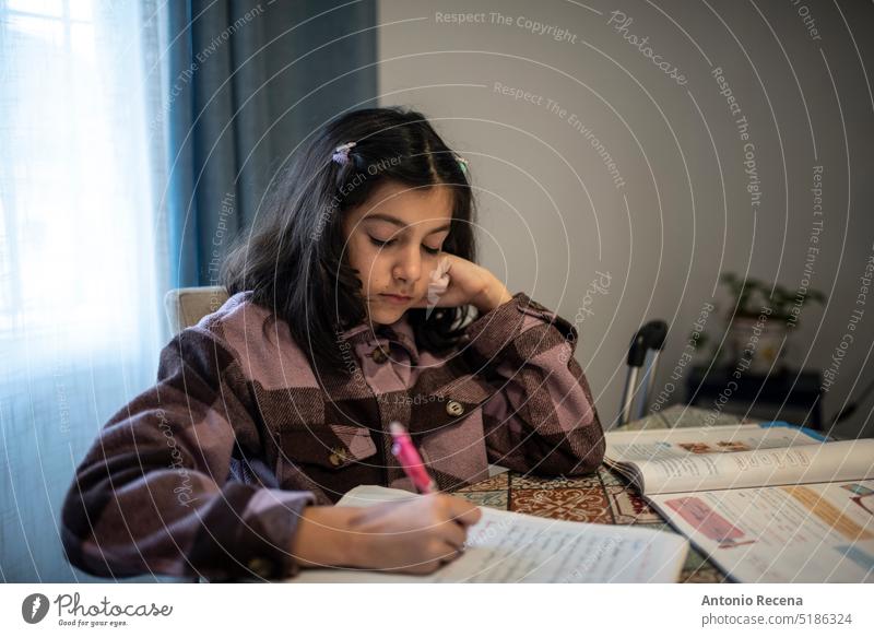 Kleines Mädchen macht zu Hause Hausaufgaben, schreibt und lernt Menschen Person Bildung im Innenbereich Lebensstile Frau hübsch lässig sitzen Tisch heimwärts