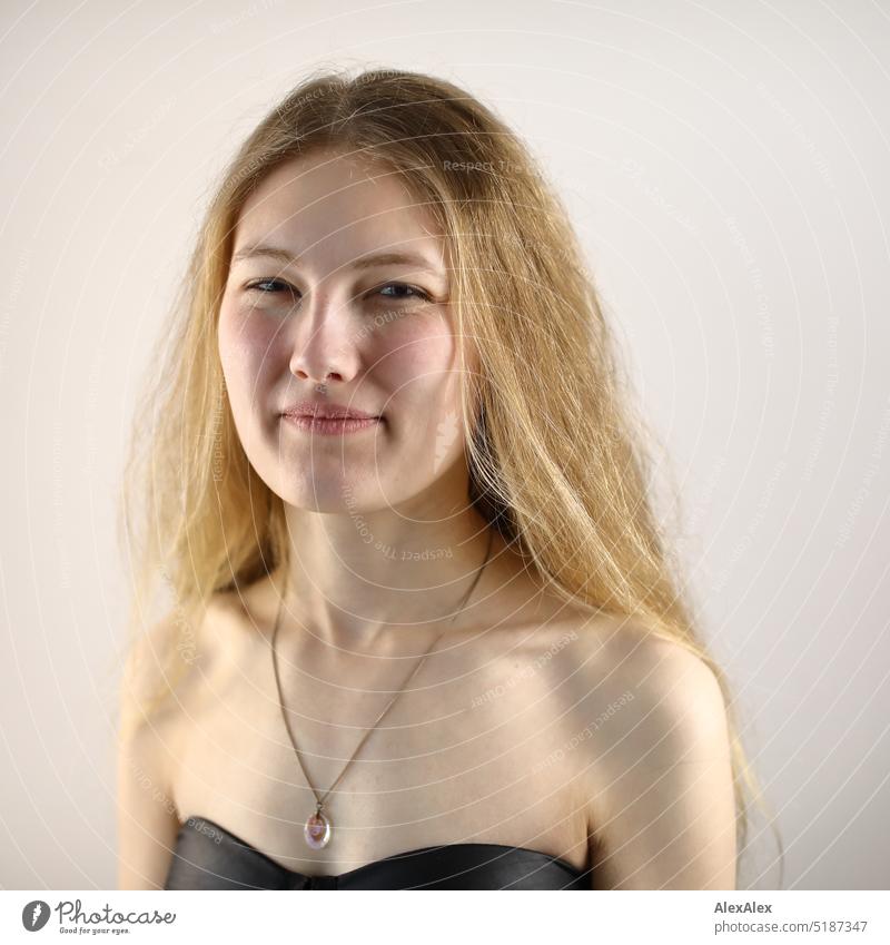 Nahes Portrait einer jungen, blonden Frau, die  vor einem weißen Hintergrund steht frisch Blick in die Kamera Erwartung drinnen Selbstbewußt weiblich charmant